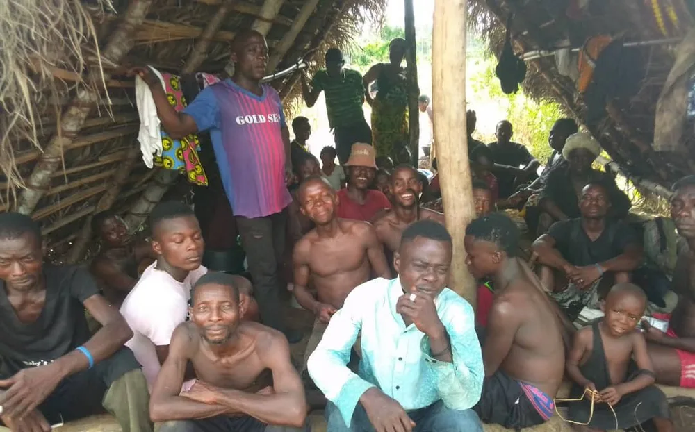 A village work crew gathered together under a thatched shelter